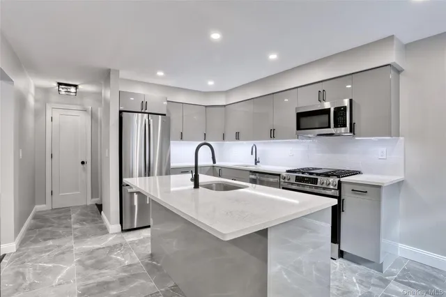 a large kitchen with stainless steel appliances granite countertop a stove refrigerator and a sink