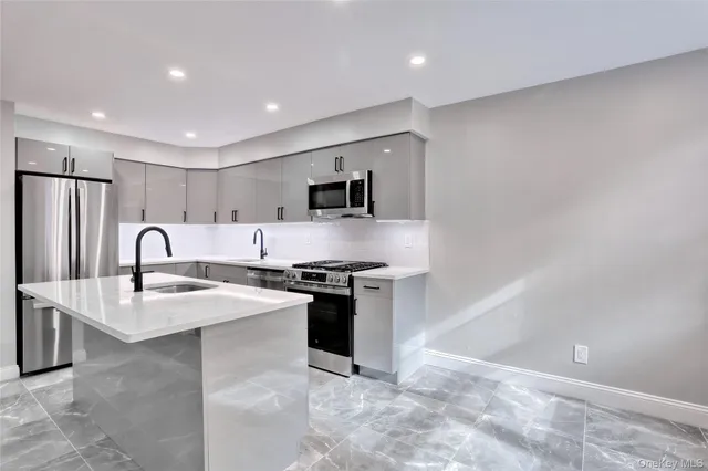 a large kitchen with stainless steel appliances granite countertop a sink a stove a refrigerator and a refrigerator