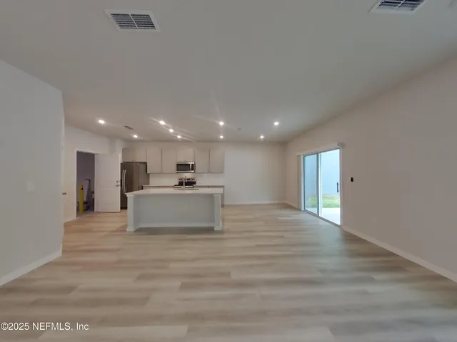 a big room with kitchen view and a refrigerator