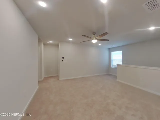 an empty room with a fan & a window