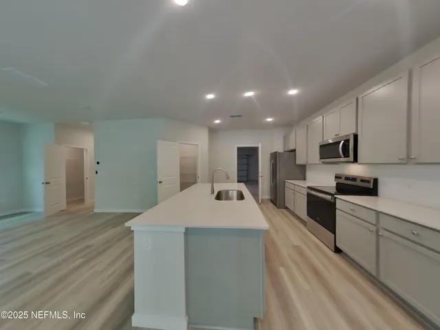 a large kitchen with kitchen island a sink stainless steel appliances and cabinets