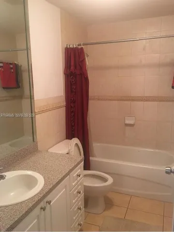 a bathroom with a granite countertop bathtub sink vanity mirror and toilet