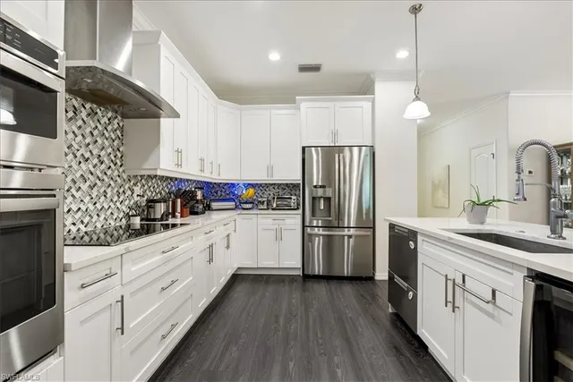 a kitchen with kitchen island a stove a sink a refrigerator and chairs with wooden floor