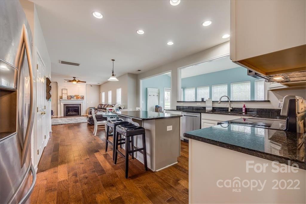 612 Panthers Way Fort Mill, SC 29708 - Photo 8 of 31 a kitchen with stainless steel appliances granite countertop a stove top oven a sink dishwasher a dining table and chairs with wooden floor
