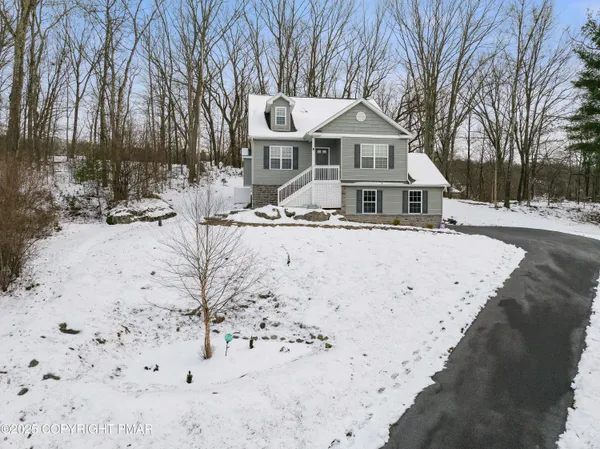 a front view of a house with a yard covered in snow