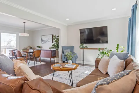 a view of a dining room and livingroom with furniture wooden floor a rug a fireplace and a chandelier