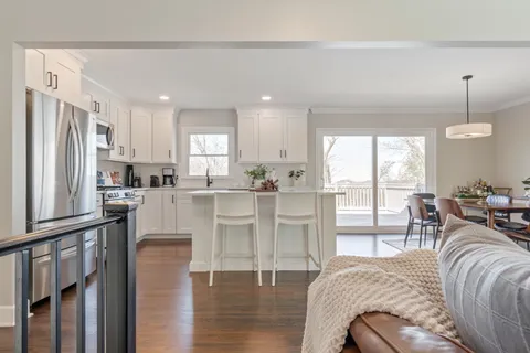 a kitchen with a table chairs wooden floors and white stainless steel appliances