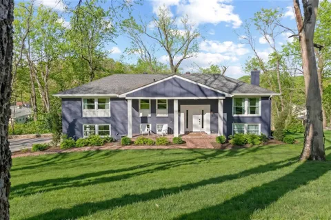a front view of a house with a garden and trees