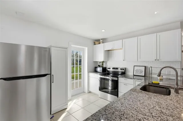 a kitchen with granite countertop a refrigerator stove and sink