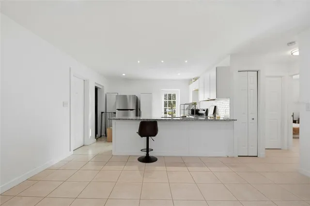 a living room with stainless steel appliances kitchen island granite countertop furniture and a refrigerator