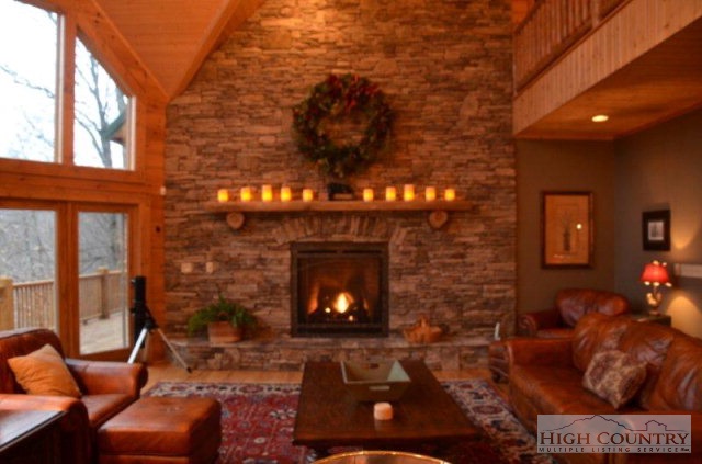 495 Mulberry Mountain Road Boone, NC 28607 - Photo 24 of 36 a living room with furniture a fireplace and a floor to ceiling window