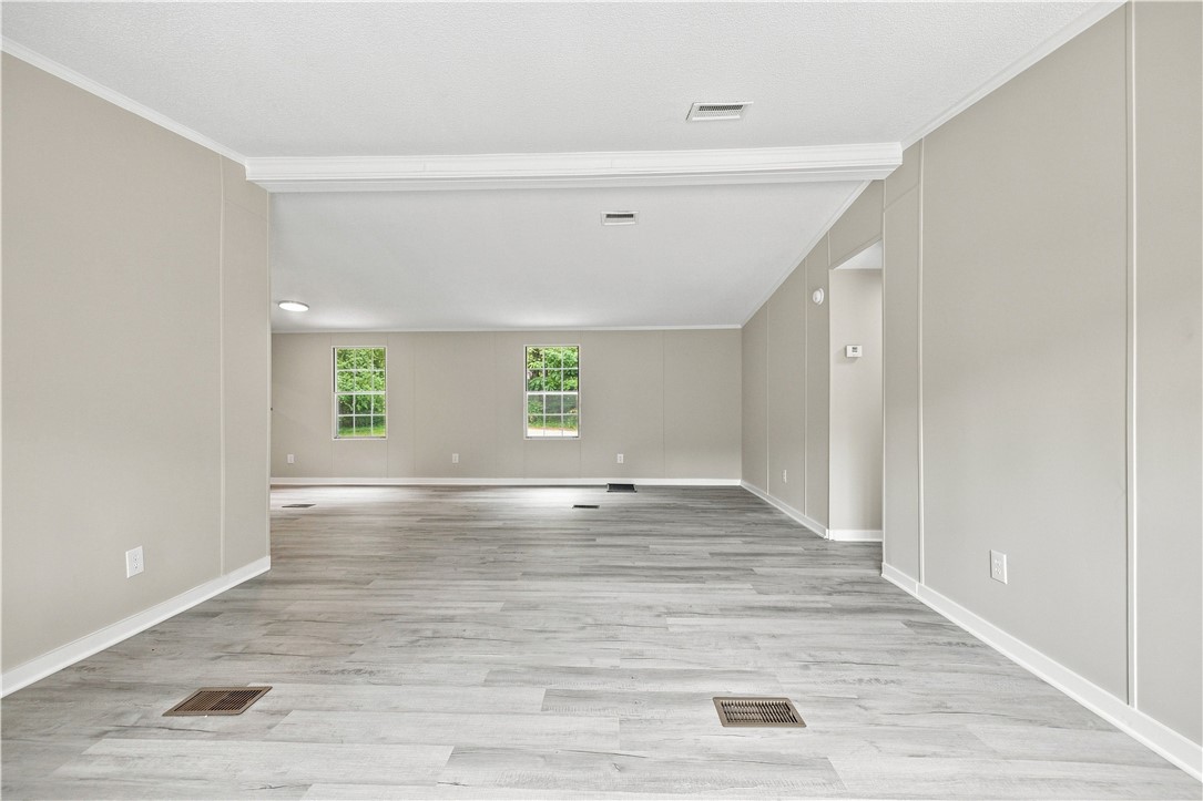 Crisp crown molding accents the neutral walls and wood-look flooring of this spacious open living area.