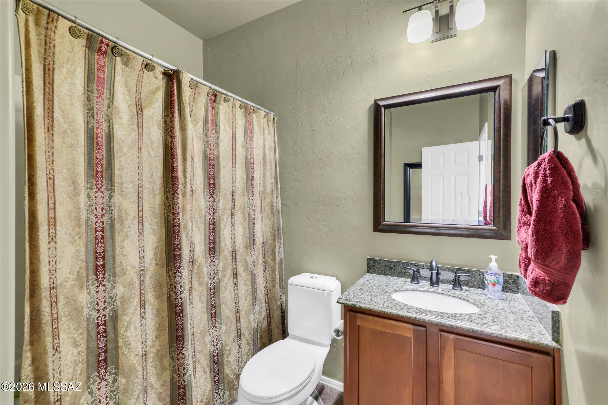 6095 South Jakemp Trail Tucson, AZ 85747 - Photo 15 of 52 a bathroom with a granite countertop sink vanity mirror and a toilet