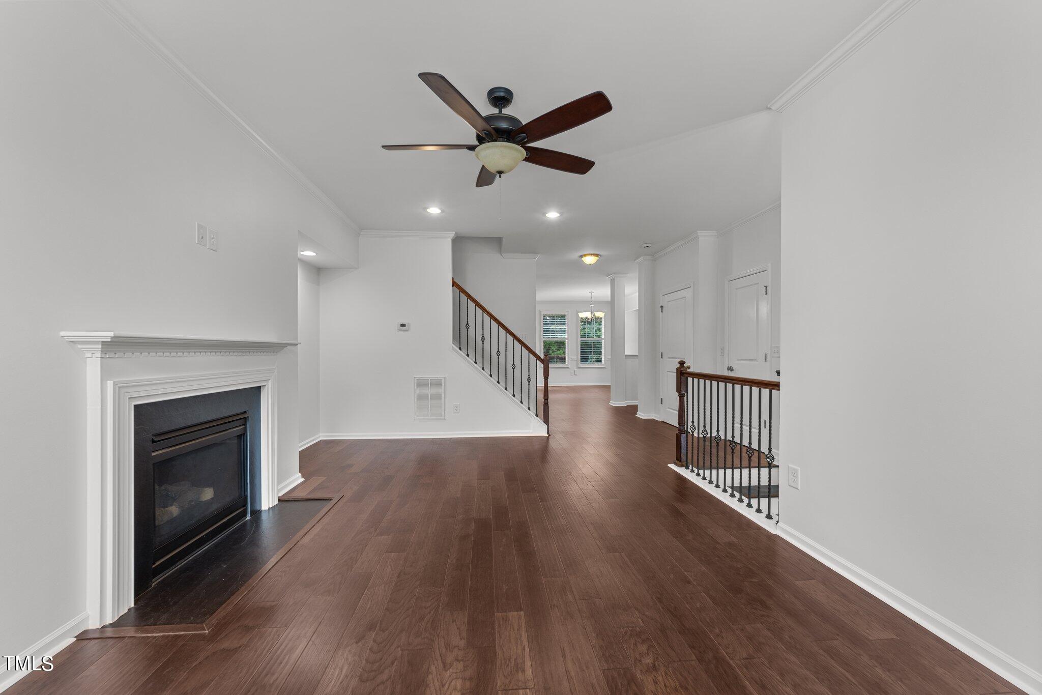5627 Wade Park Boulevard Raleigh, NC 27607 - Photo 7 of 44 an empty room with wooden floor a ceiling fan and a fireplace