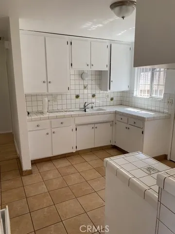 a kitchen with white cabinets a sink dishwasher and a stove