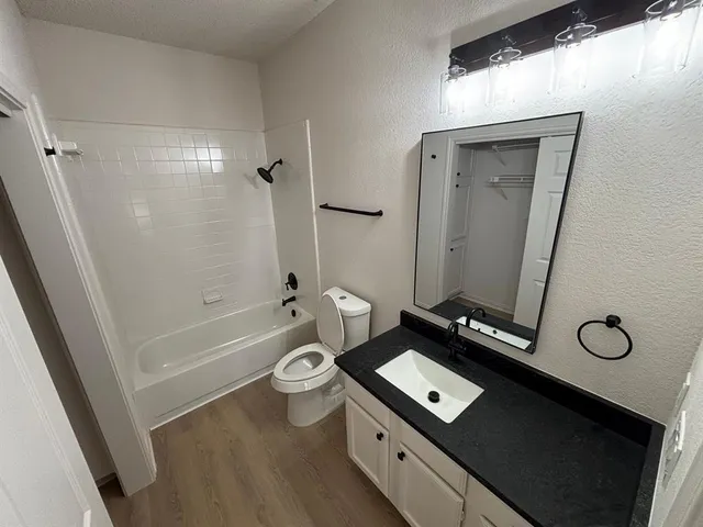 a bathroom with a granite countertop sink a toilet a mirror and shower