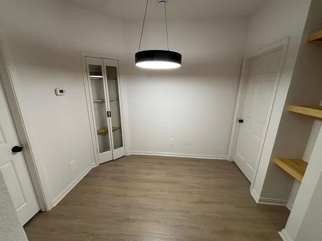 an empty room with wooden floor and window