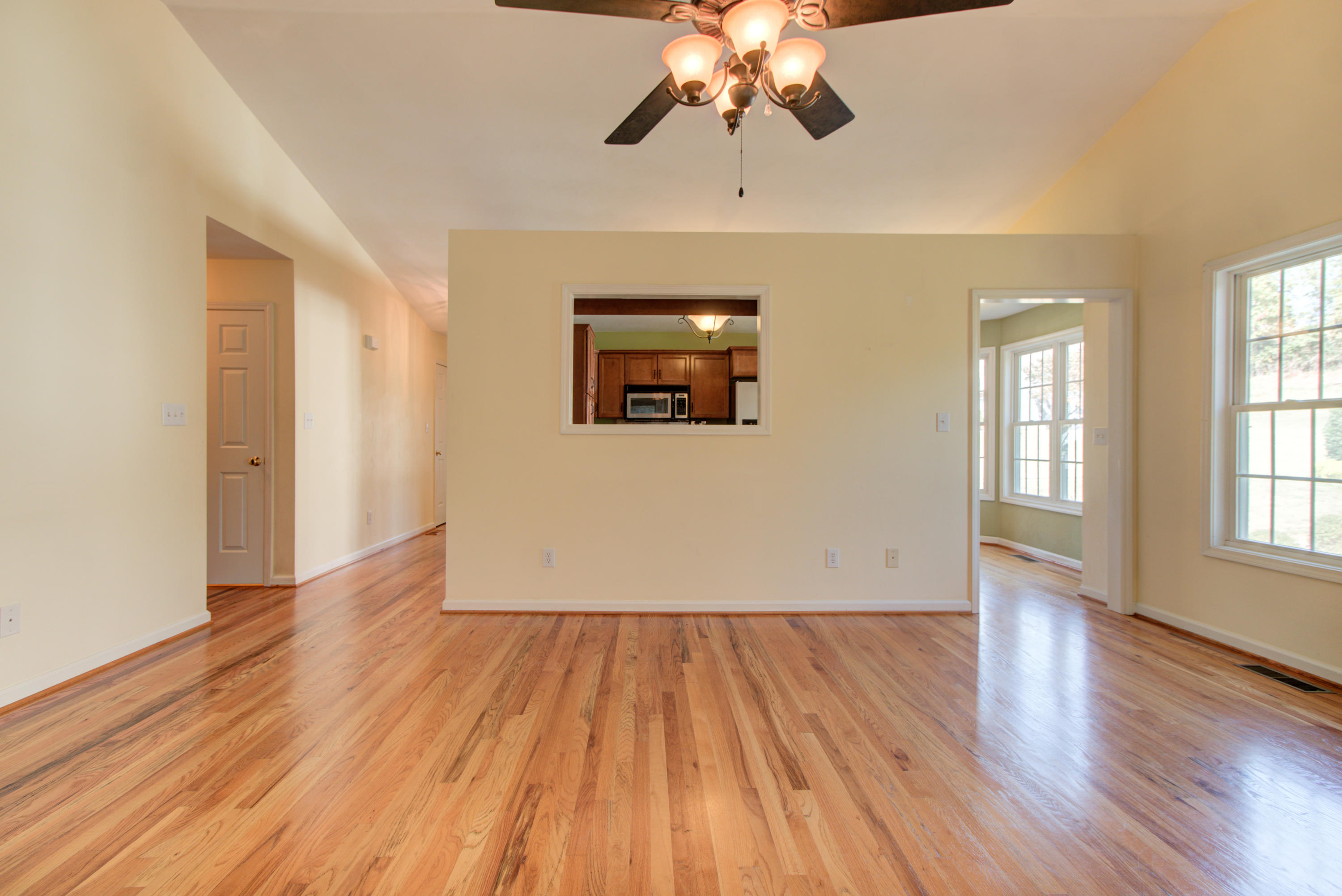 1781 Meadows Road Vinton, VA 24179 - Photo 12 of 26 an empty room with wooden floor chandelier fan and windows