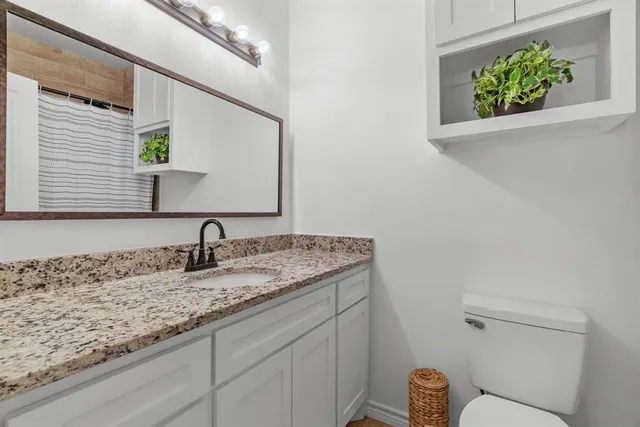 a bathroom with a granite countertop sink and a toilet