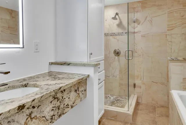 a bathroom with a granite countertop sink a mirror and shower