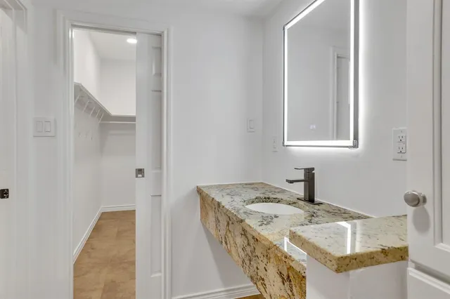 a en suite bathroom with a granite countertop sink and a mirror