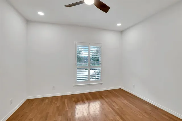 an empty room with wooden floor cabinet and windows