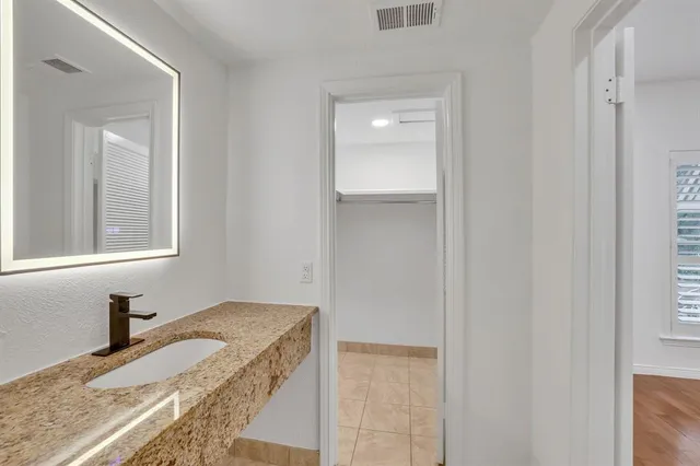 a bathroom with a granite countertop sink and a mirror