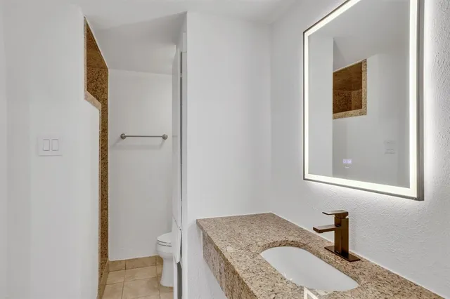 a bathroom with a granite countertop sink and a toilet