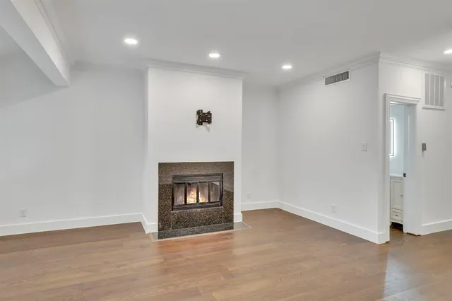 a view of an empty room with wooden floor and a fireplace