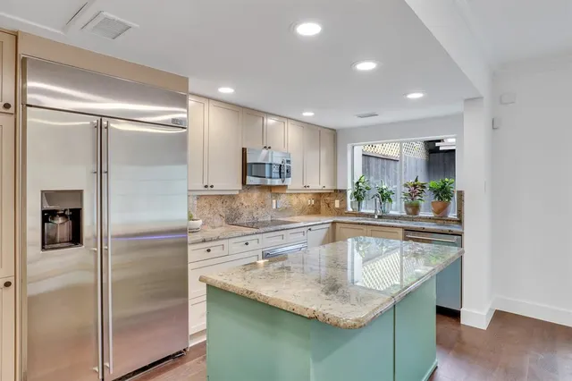 a kitchen with kitchen island granite countertop a refrigerator and a sink