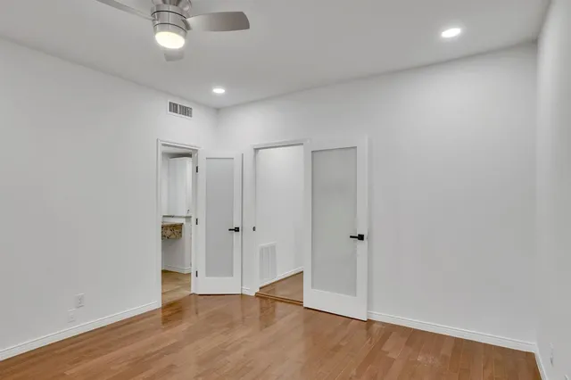 an empty room with wooden floor and a ceiling fan