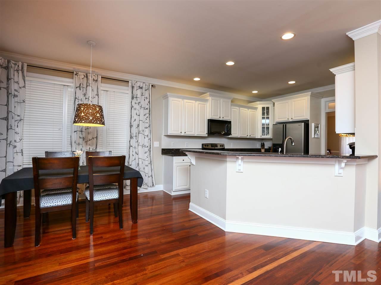 2220 Karns Place Raleigh, NC 27614 - Photo 5 of 25 a kitchen with stainless steel appliances granite countertop a stove top oven a refrigerator a dining table and chairs with wooden floor