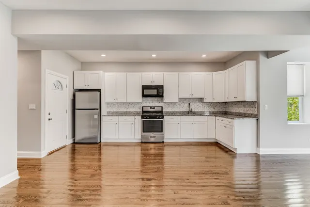 a kitchen with stainless steel appliances granite countertop a refrigerator sink and white cabinets