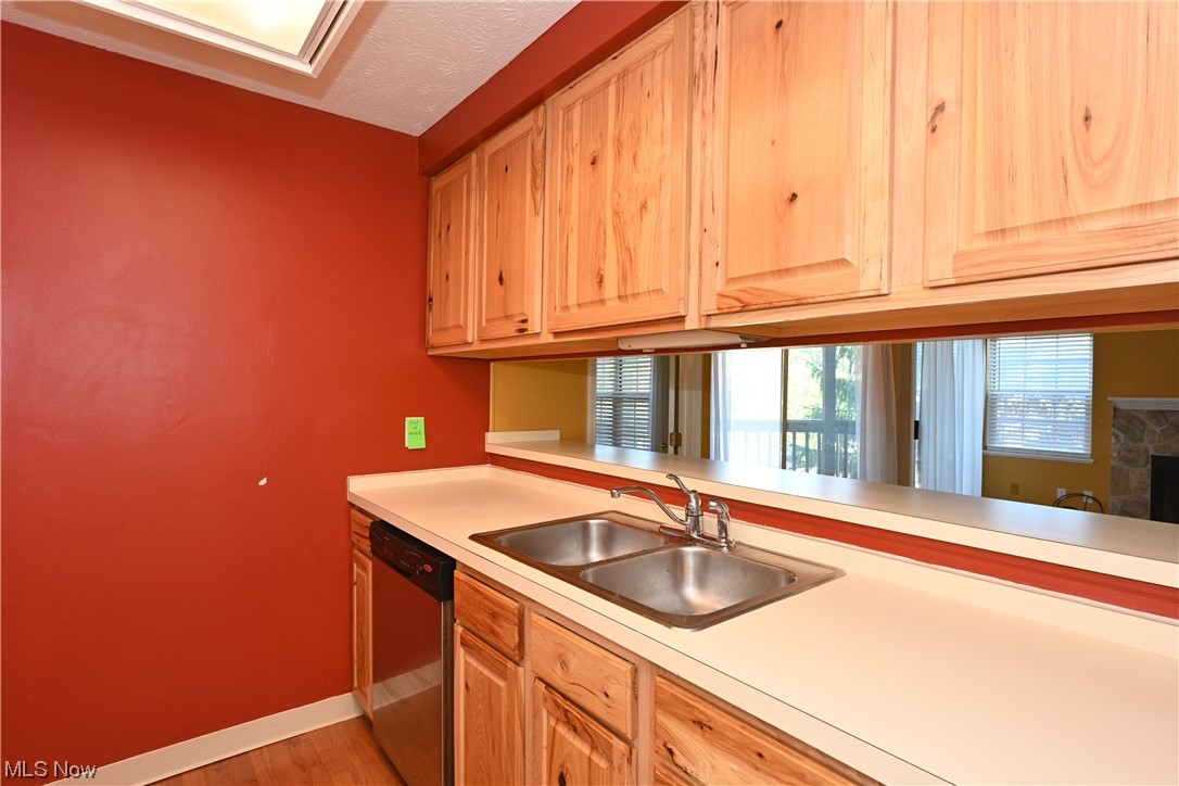 28140 Detroit Road, Unit A1 Westlake, OH 44145 - Photo 14 of 30 Kitchen with stainless steel dishwasher, sink, light hardwood floors, and a stone fireplace