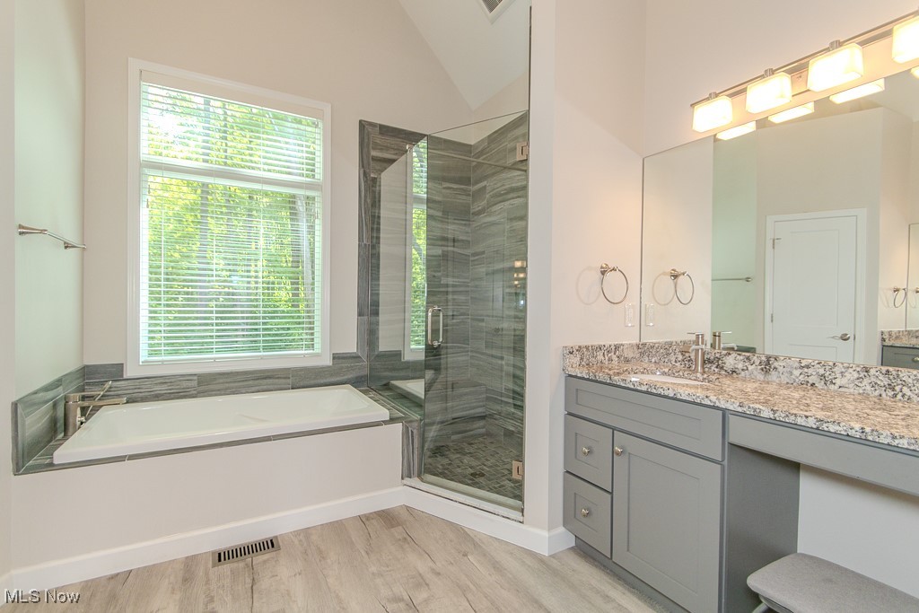 8675 Auburn Road Chardon, OH 44024 - Photo 13 of 35 Full bathroom featuring vanity, a garden tub, a stall shower, light wood-style flooring, and vaulted ceiling