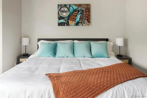 a bedroom with a bed and painting on the wall