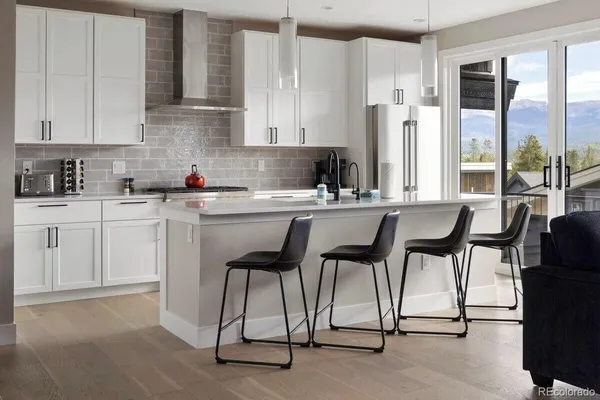 a kitchen with stainless steel appliances kitchen island a table chairs and a refrigerator