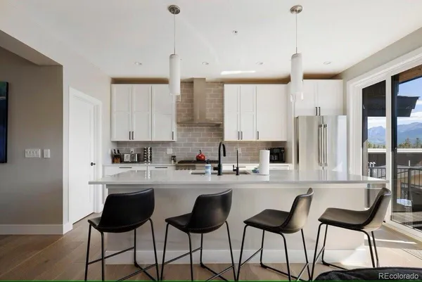 a kitchen with stainless steel appliances kitchen island granite countertop a dining table chairs and white cabinets