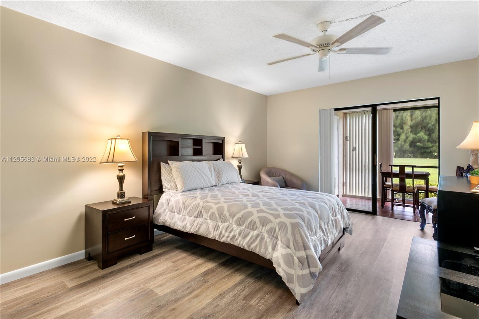101 Pinecrest Circle, Unit E Jupiter, FL 33458 - Photo 12 of 20 a bedroom with a bed a large window and wooden floor