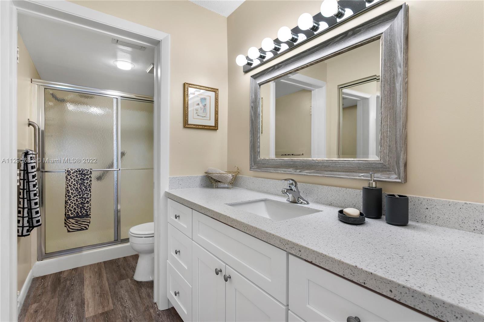 101 Pinecrest Circle, Unit E Jupiter, FL 33458 - Photo 13 of 20 a bathroom with a sink a toilet and a mirror