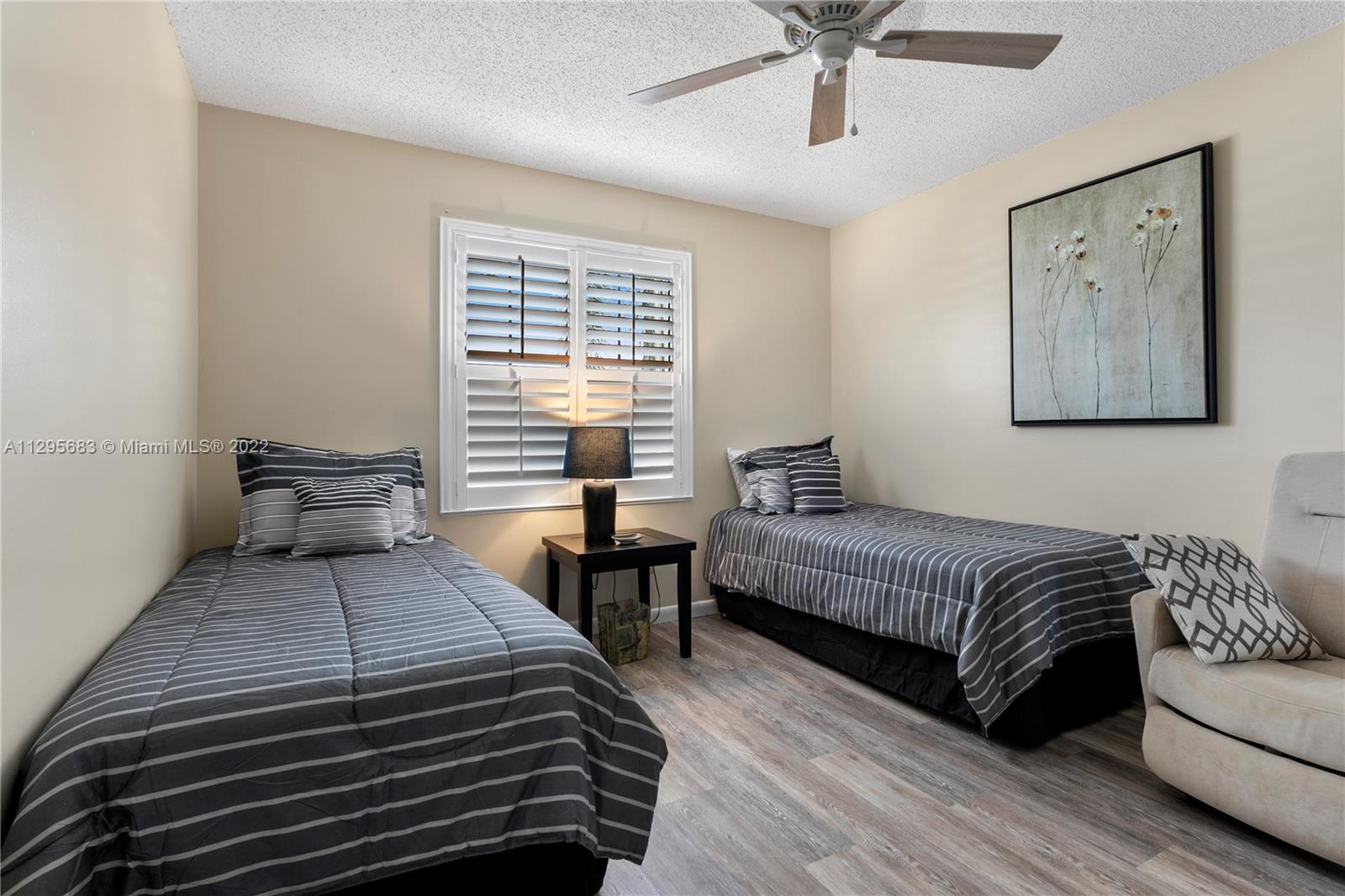 101 Pinecrest Circle, Unit E Jupiter, FL 33458 - Photo 14 of 20 a bedroom with a large bed and a chandelier