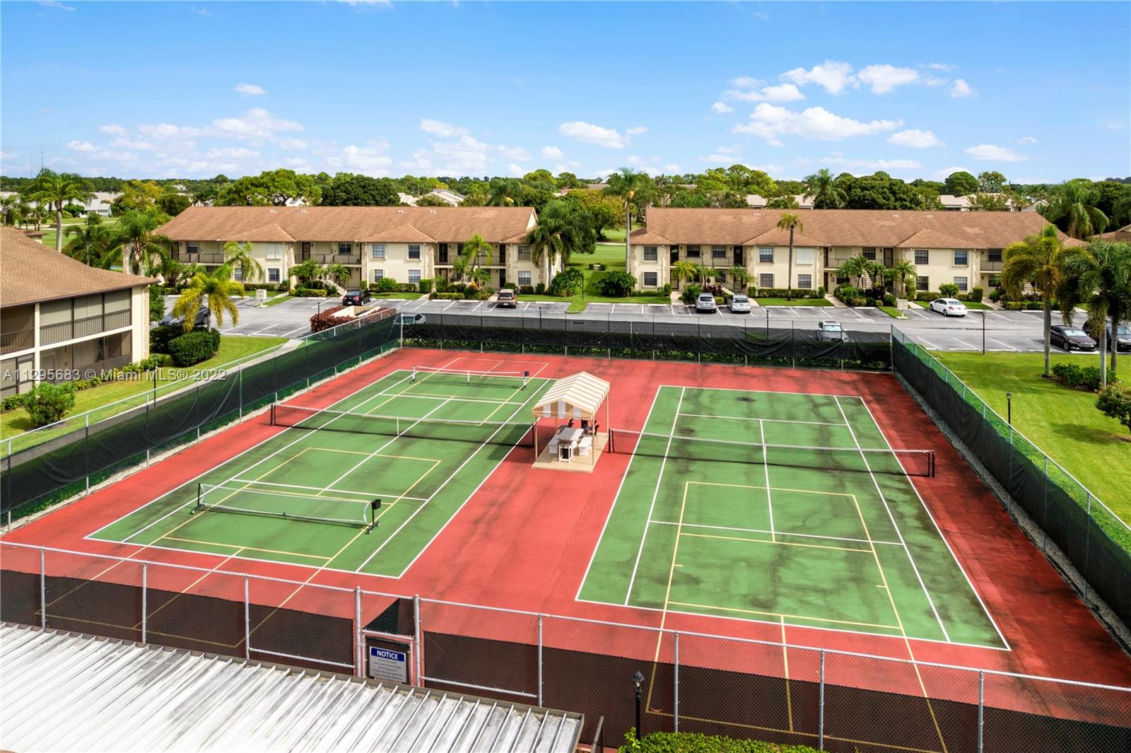 101 Pinecrest Circle, Unit E Jupiter, FL 33458 - Photo 18 of 20 a view of a tennis ground with large trees