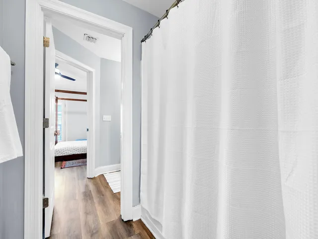 a view of a hallway with wooden floor and a bathroom