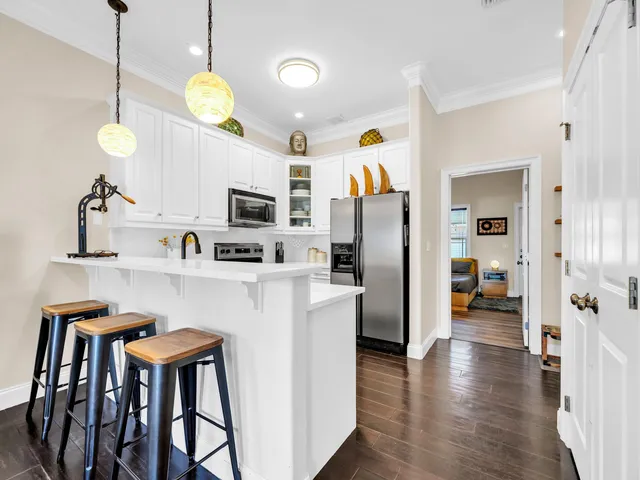 a kitchen with stainless steel appliances granite countertop a refrigerator a microwave a stove and white cabinets with wooden floor