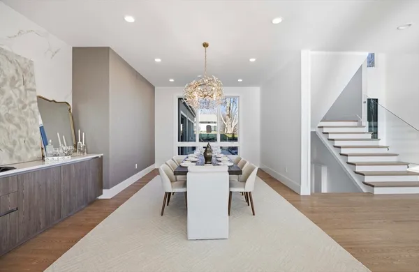 a dining room with wooden floor a chandelier a wooden table and chairs