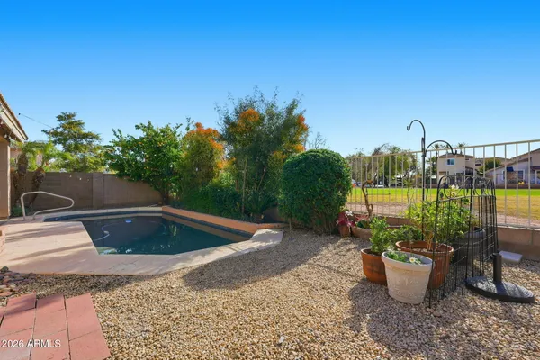 a view of a white house next to a yard with potted plants