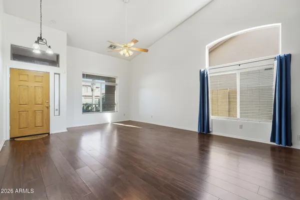 an empty room with wooden floor chandelier fan and windows