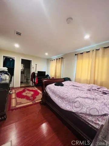 a spacious bedroom with a bed and wooden floor