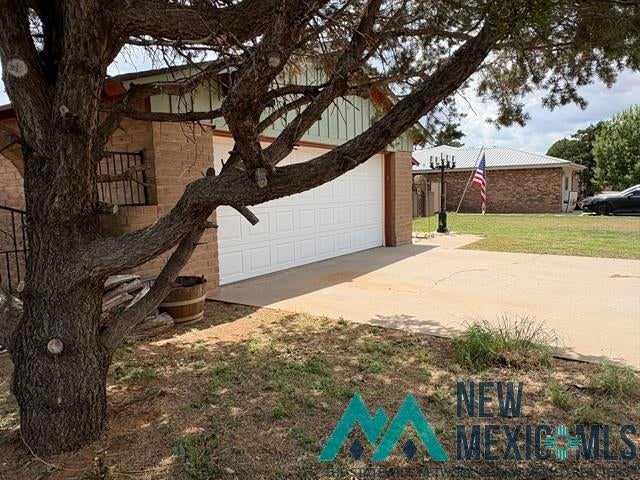 1037 Oakhurst Road Clovis, NM 88101 - Photo 3 of 21 Attached garage with a white sectional door, brick exterior facade, and a concrete driveway