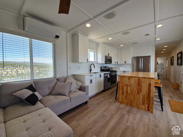 900 Altamont Road Evanston, WY 82930 - Photo 27 of 27 Kitchen with stainless steel appliances, open floor plan, a kitchen bar, an AC wall unit, and light wood-style flooring